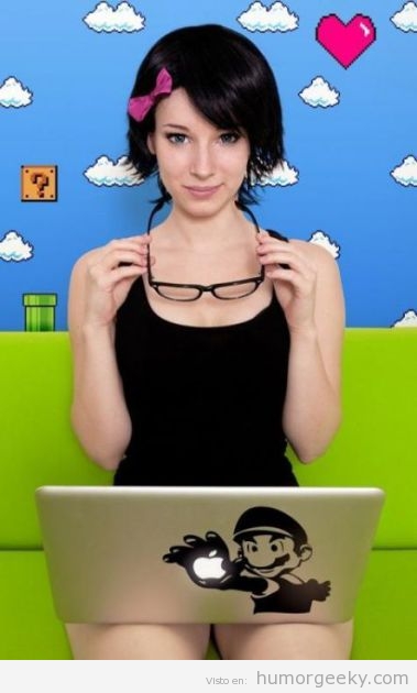 Chica guapa sentada ante un fondo de Mario Bros y juagndo con un ordenador Mac