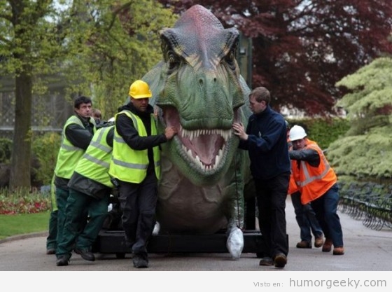 Dinosaurio empujado por unos operarios