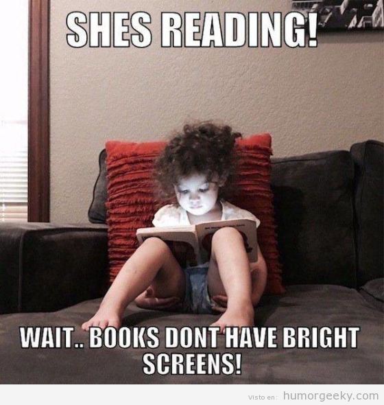 Foto graciosa niña con tablet o móvil oculta tras un libro